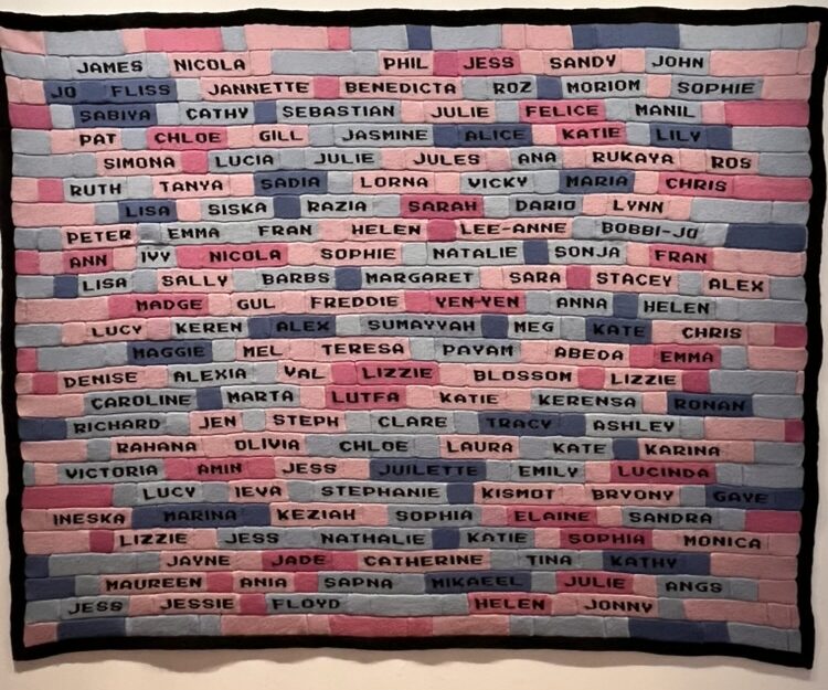 A knitted blanket that looks like bricks with contributors' names on them